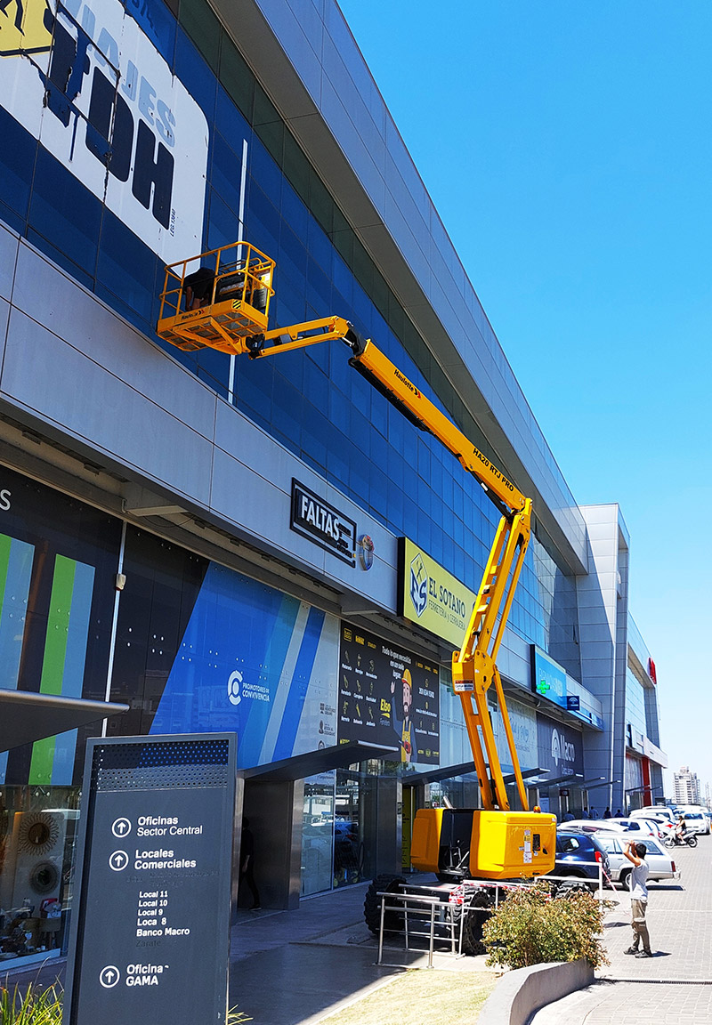 Brazo articulado trabajando sobre fachada comercial