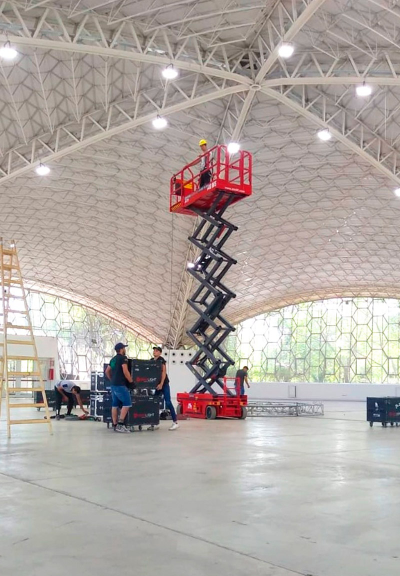 Plataforma de tijera roja trabajando en armado de evento