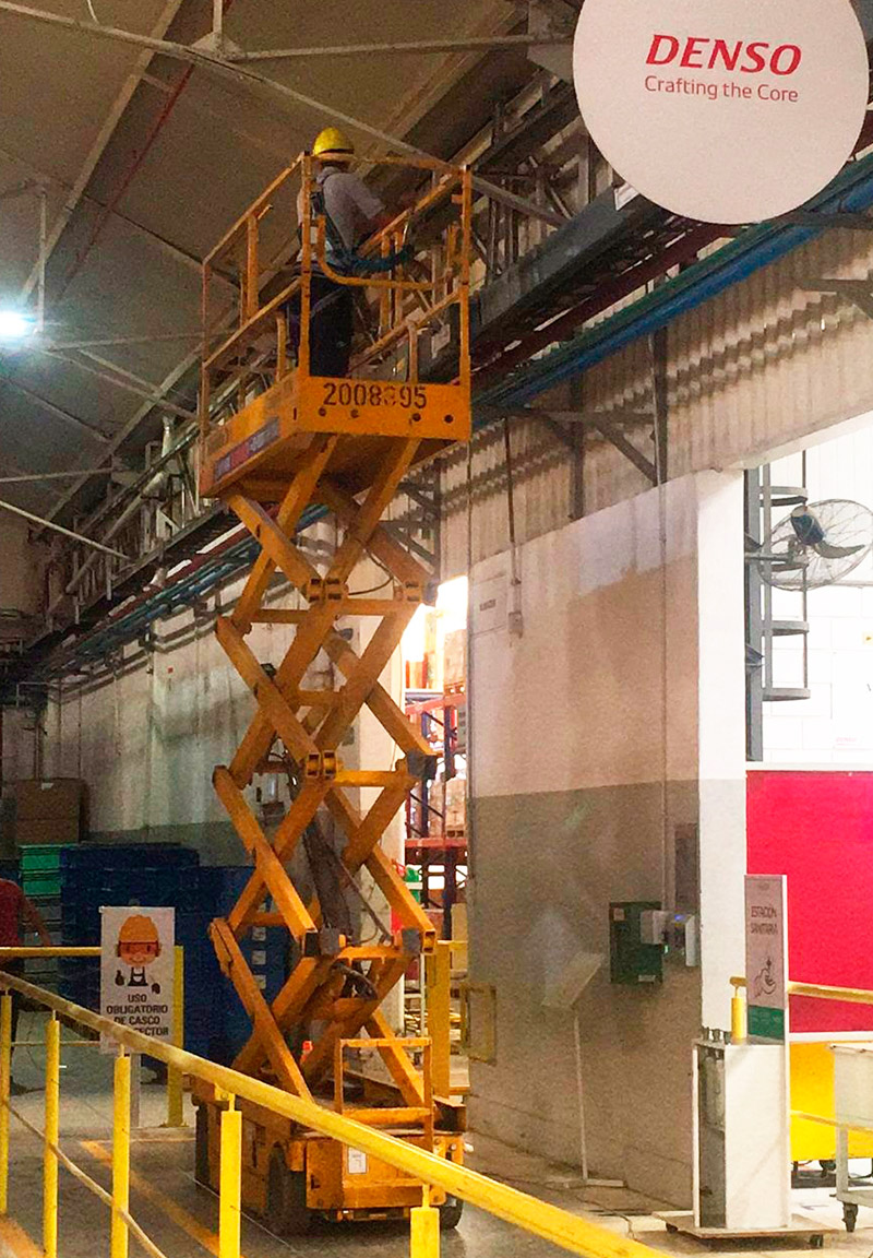 Plataforma de tijera elevando operario en industria